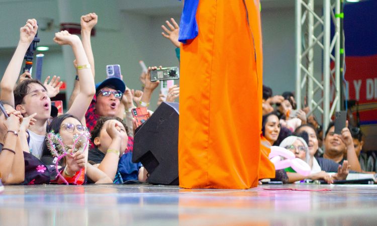 Personnes au bord d’un podium soutenant une autre personne en cosplay