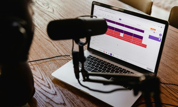Micro sur pied noir flou au premier plan, logiciel de montage audio net au second plan