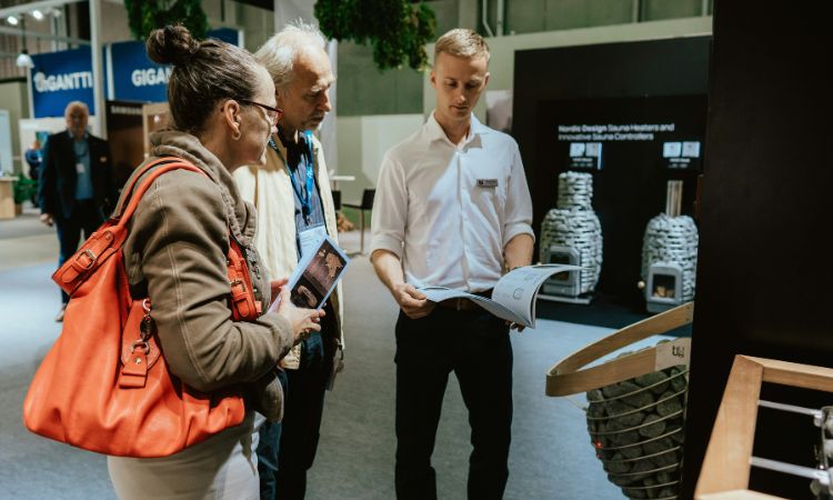 Deux personnes sur un stand de poêle à bois discutant avec un représentant sur un salon