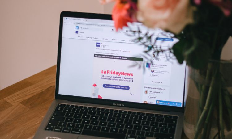 Ordinateur portable sur une table en bois affichant une page LinkedIn